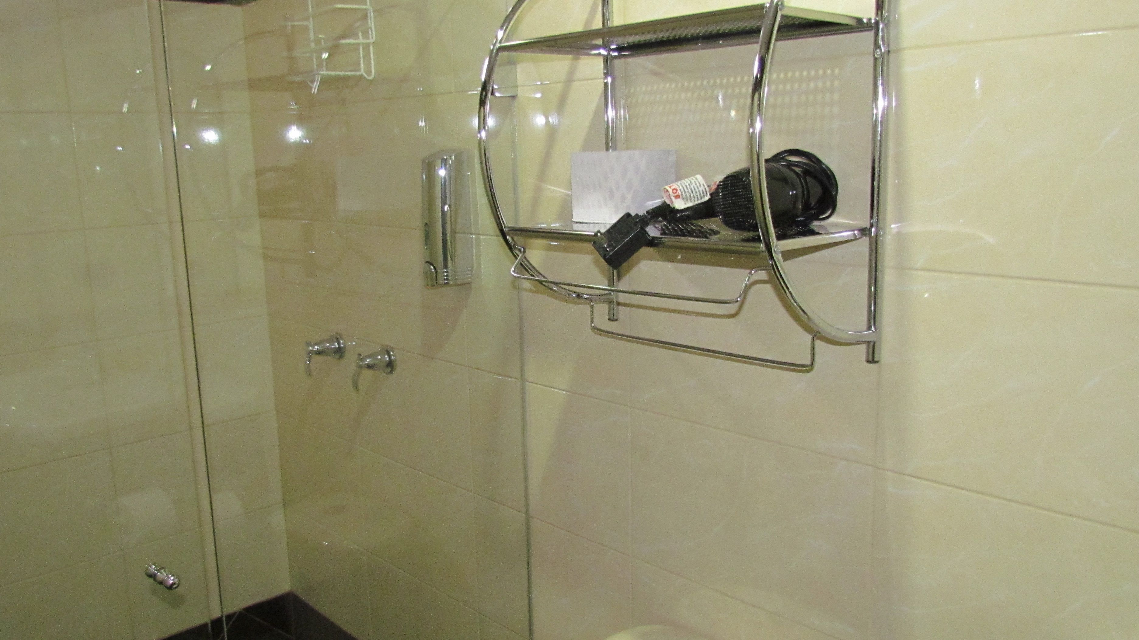 A bathroom with a glass shower enclosure, a chrome towel rack, and a towel dispenser.