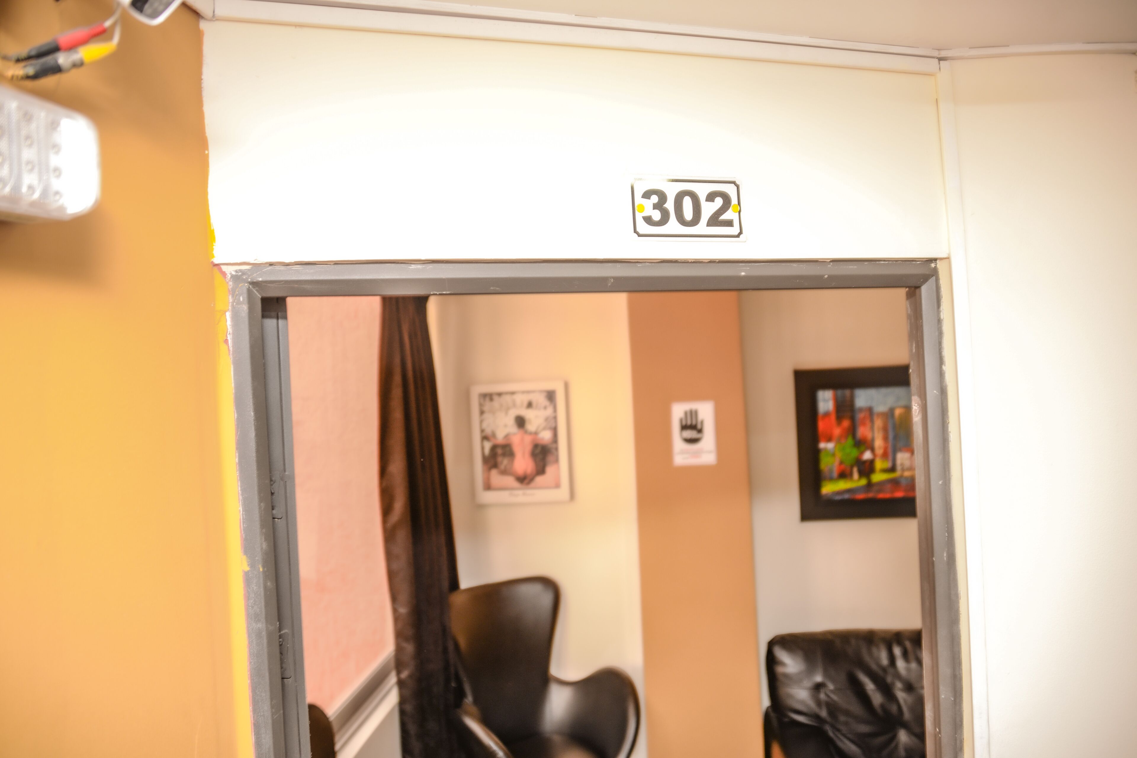 A room with a door labeled "302" and a black leather chair.