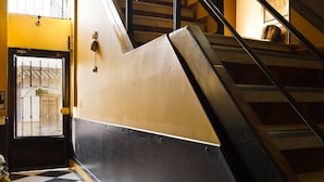 Escada com corrimão preto e parede amarela, que leva a um andar superior.