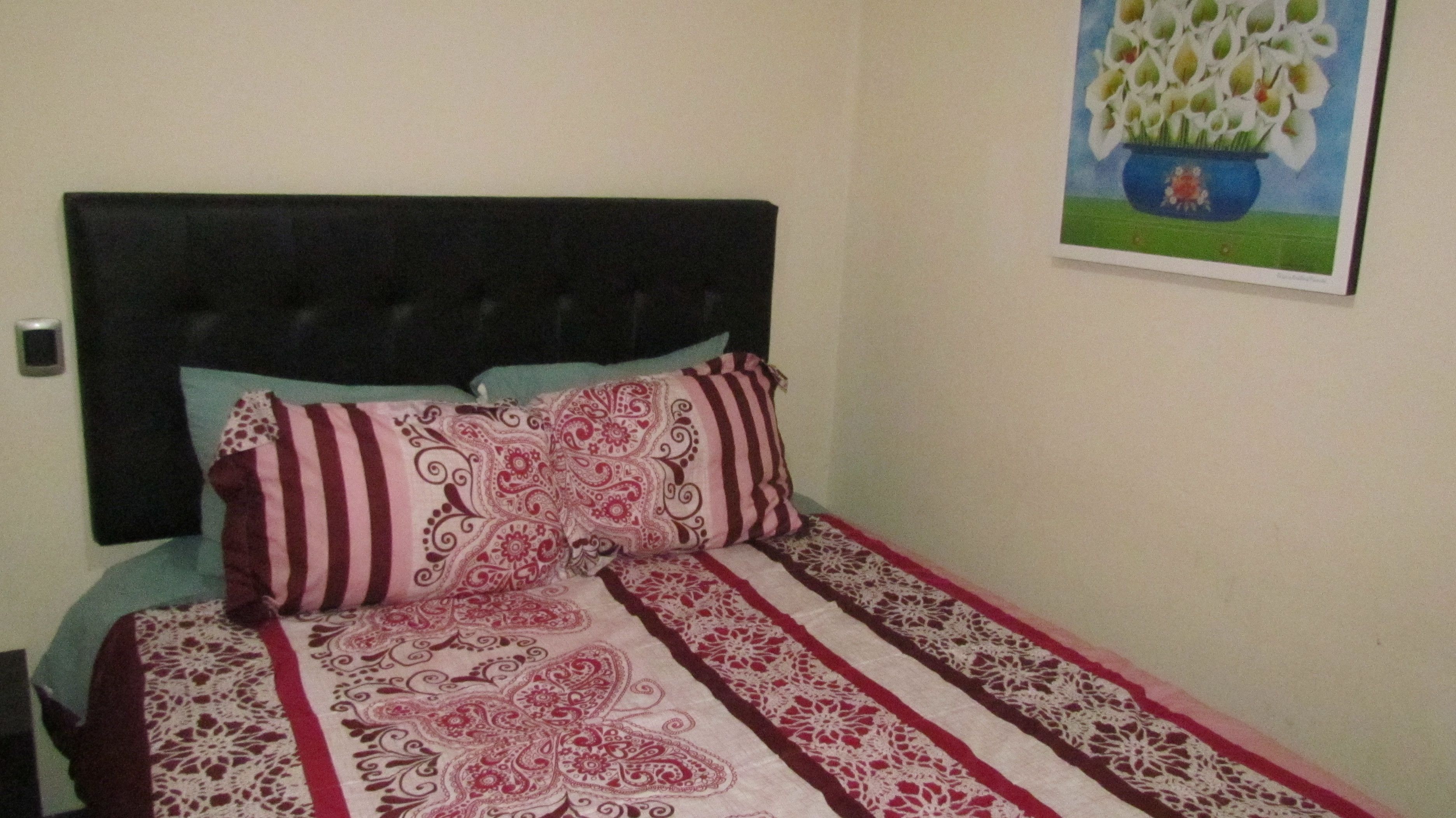 Ein Schlafzimmer mit Bett, Kopfteil und einem Wandbild.