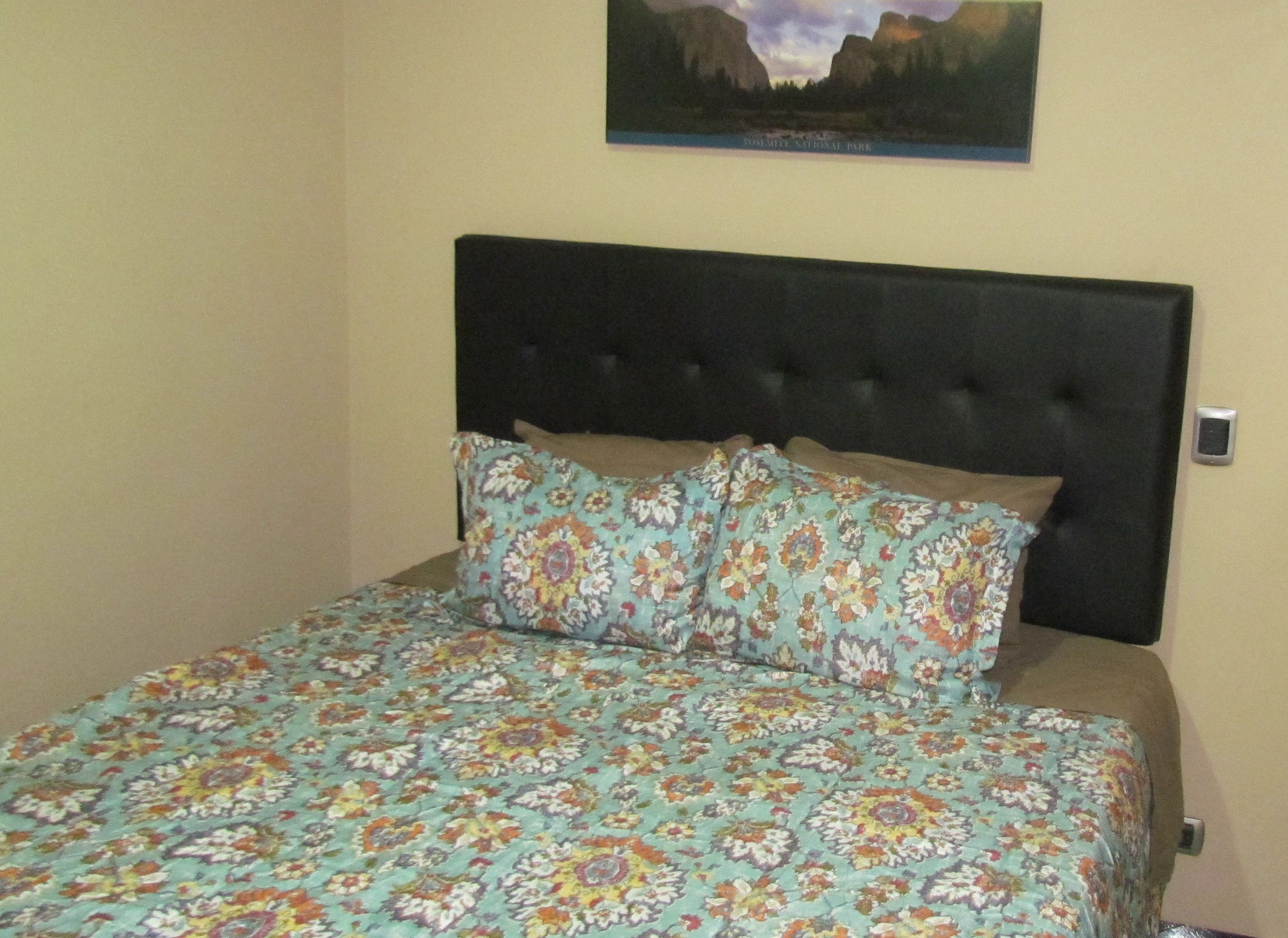 A bed with a floral bedspread and a black headboard.