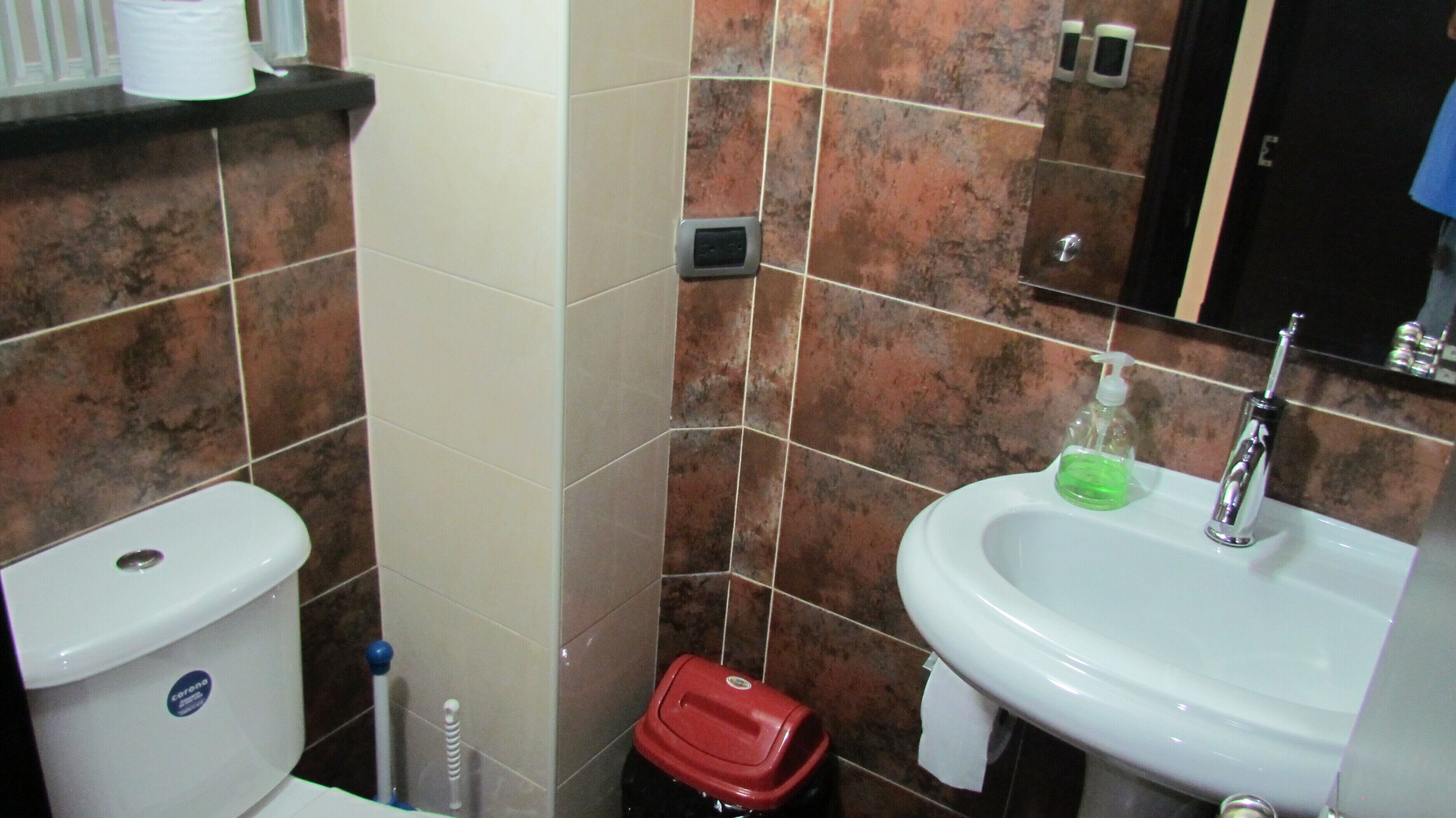 A bathroom with a toilet, sink, and hand dryer.