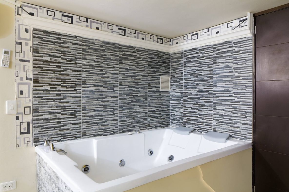 Ein modernes Badezimmer mit freistehender Badewanne, gefliesten Wänden und einer Holztür.