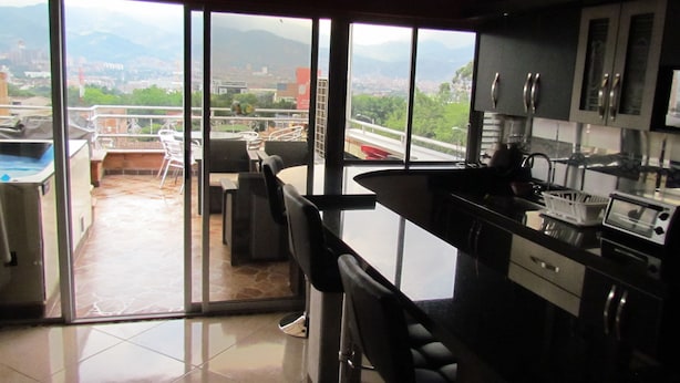 Cozinha moderna com uma grande janela que oferece vista para a cidade e montanhas.