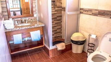 Un baño con tocador de madera, ducha y retrete.