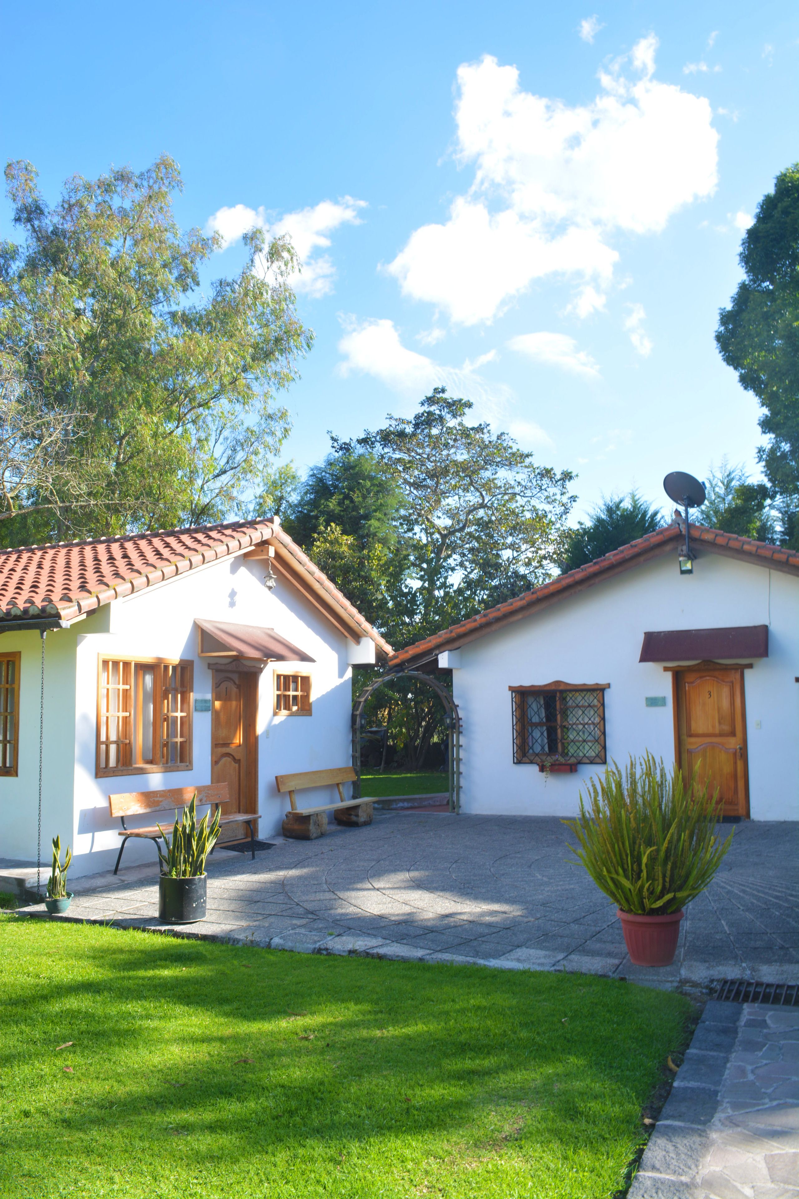 A two-story house with a tiled roof, a satellite dish, and a well-maintained lawn.