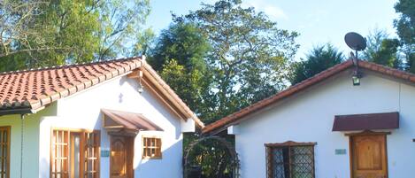 A two-story house with a tiled roof, a satellite dish, and a well-maintained lawn.