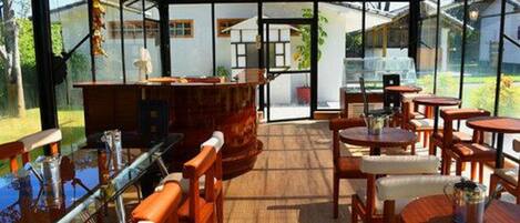 Un restaurante con cerramiento de vidrio, muebles de madera y vistas al exterior.