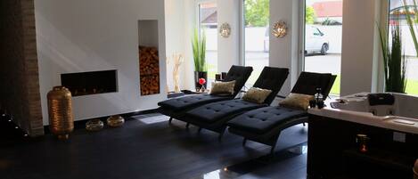 A modern spa area with a fireplace, lounge chairs, and a reception desk.