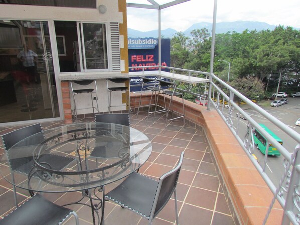 A balcony with a glass table and chairs, a view of the street below, and a sign reading "Feliz Navidad".