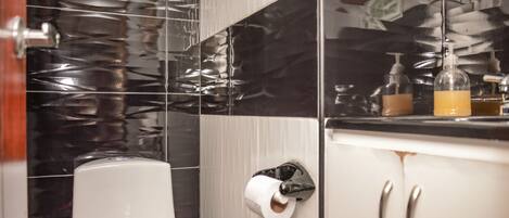Une salle de bain équipée de toilettes, d’un distributeur de gel hydroalcoolique et d’un distributeur de savon sur le comptoir.