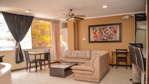 A living room with a sectional sofa, a coffee table, and a dining area with chairs. - 10A Apartments (Medellín)