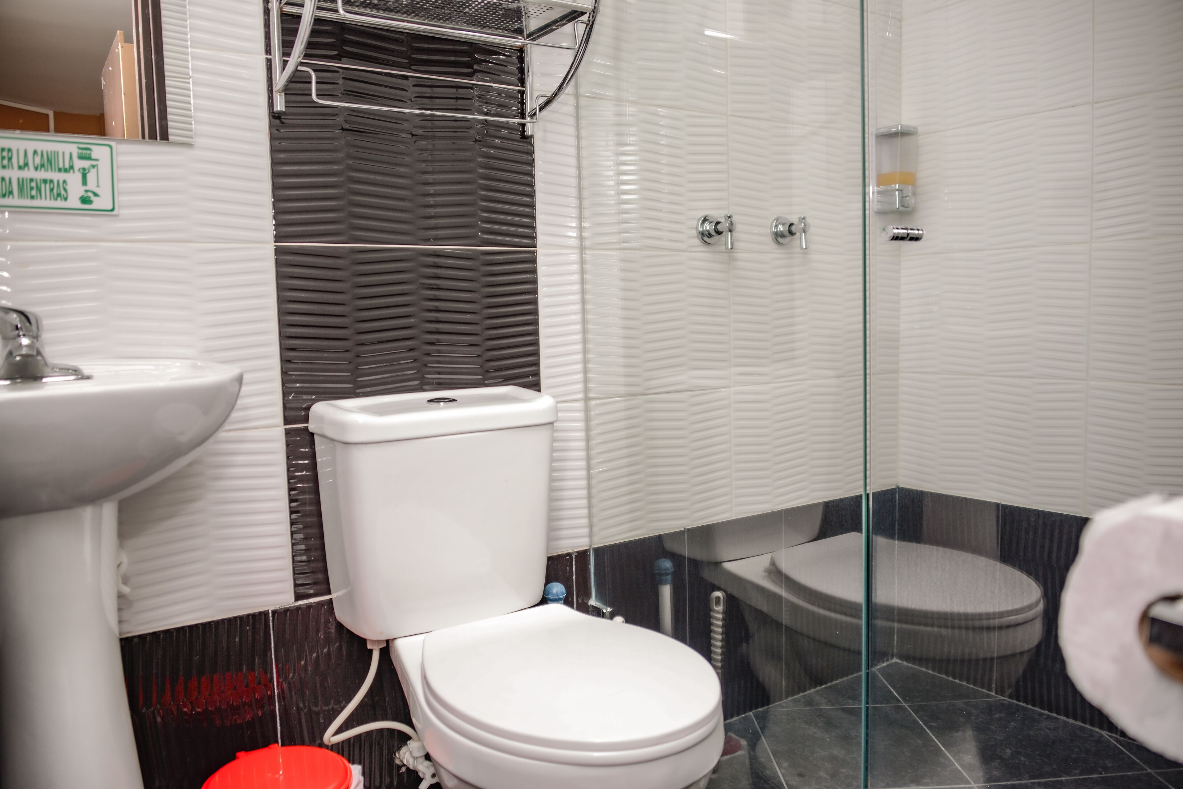 A modern bathroom with a white toilet, a glass shower enclosure, and a sink.