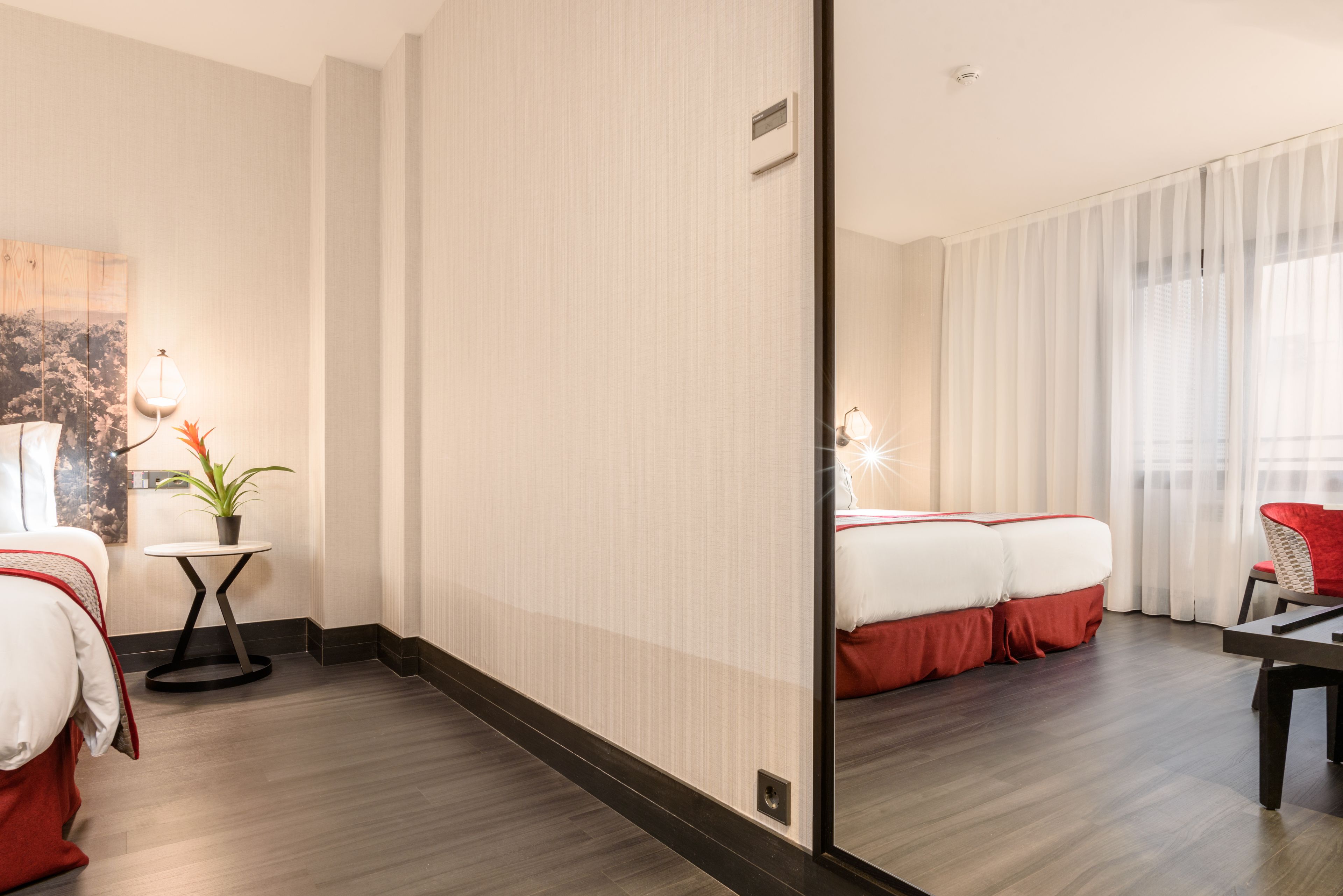 Una habitación de hotel con una cama grande, una mesita con una planta, una silla y un escritorio.