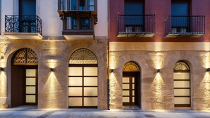 Fachada de edificio con arcos y balcones, iluminada por luces empotradas.