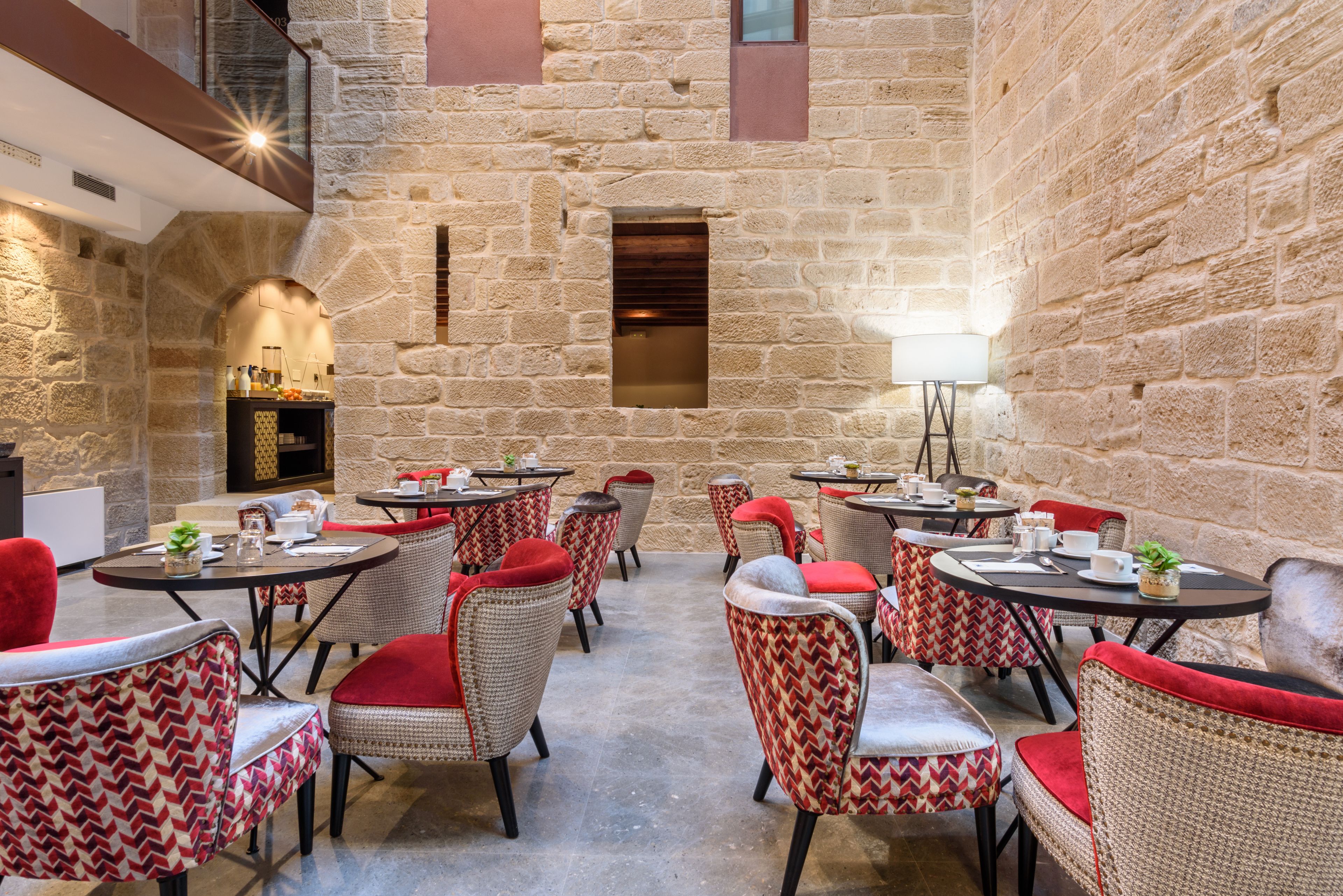 Un cortile interno con pareti in pietra, mobili in vimini e tavoli apparecchiati per la cena.