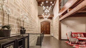 Un interior moderno con paredes de ladrillo visto, una escalera, una puerta de madera y un sofá rojo.