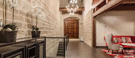 Um interior moderno com paredes de tijolo aparente, uma escada, uma porta de madeira e um sofá vermelho.