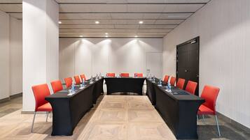 A conference room with a long table, red chairs, and a black tablecloth.