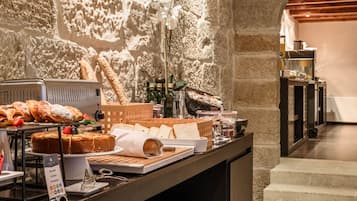 A buffet setup with bread, pastries, and bottles of beverages.