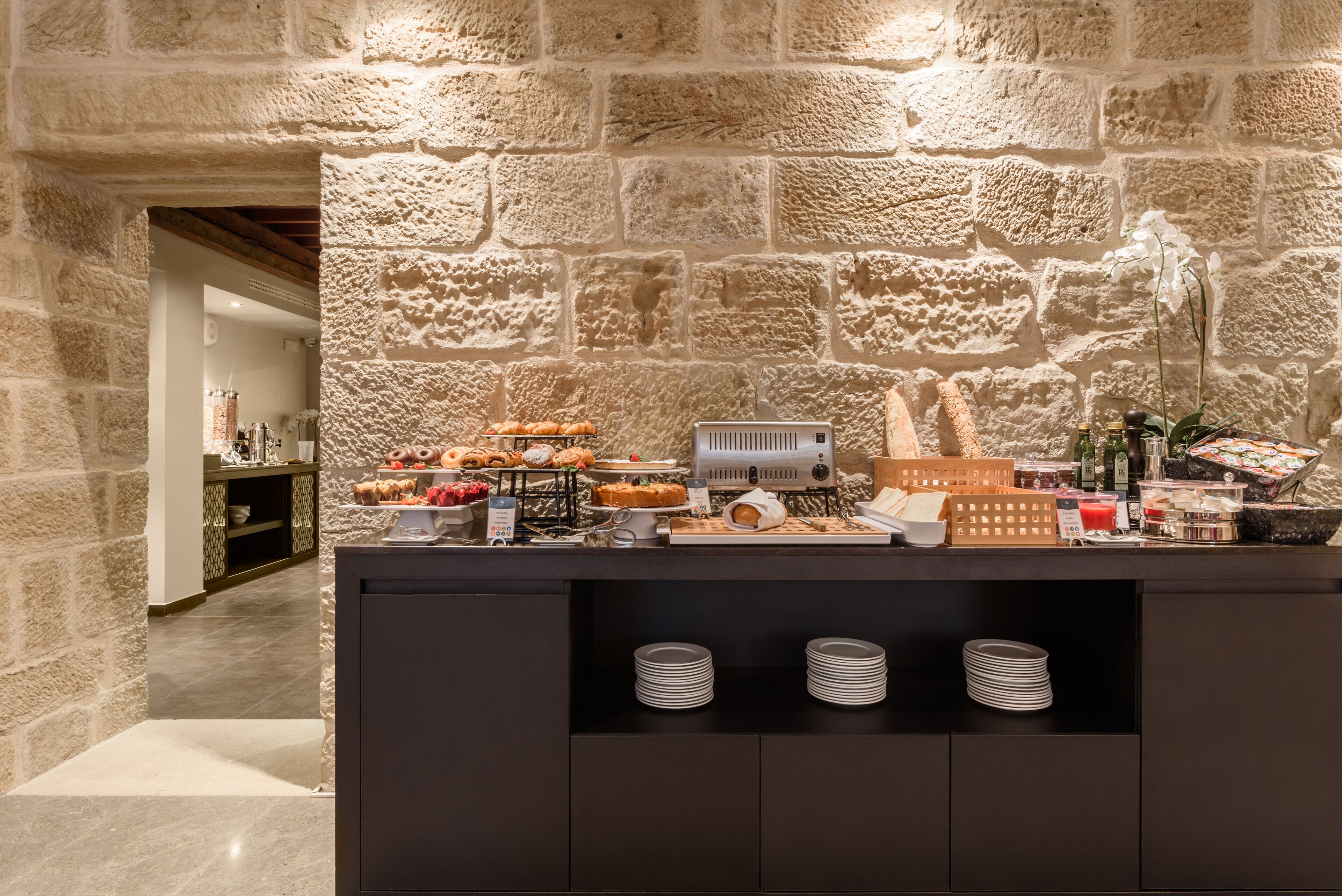 Un espace buffet avec un mur en pierre servant de décor, une variété de plats et des assiettes soigneusement empilées.