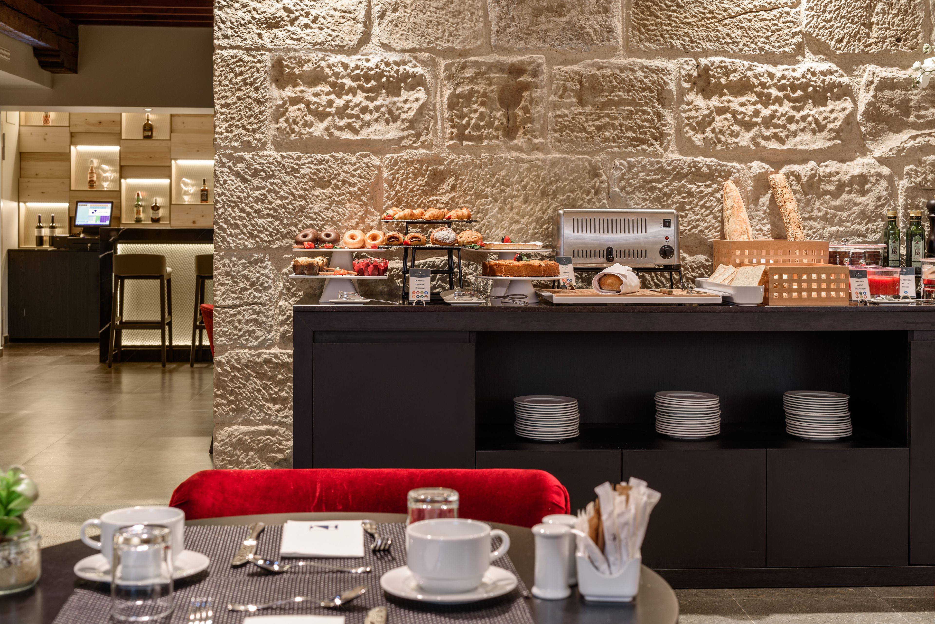 A breakfast buffet with pastries, a coffee station, and a counter with a computer.
