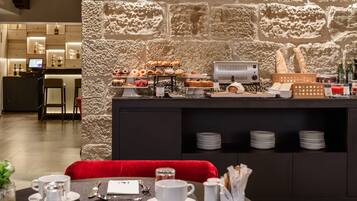 A breakfast buffet with pastries, a coffee station, and a counter with a computer.