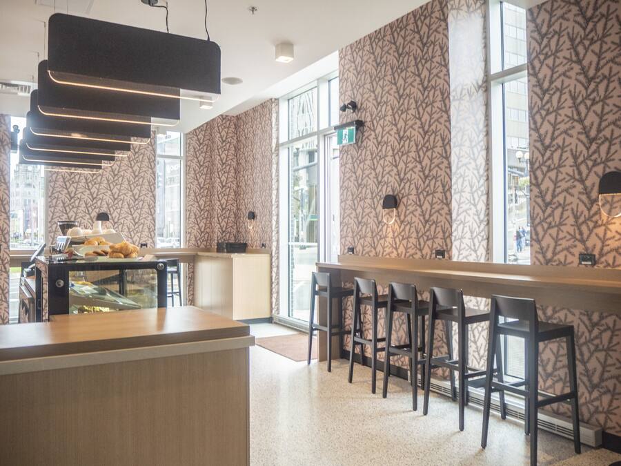 A modern bar area with a patterned wallpaper, a counter with a glass display case, and a seating area with bar stools.
