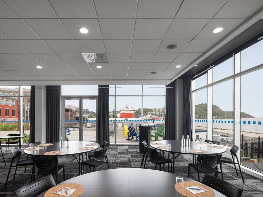 A conference room with large windows, round tables, and black chairs.
