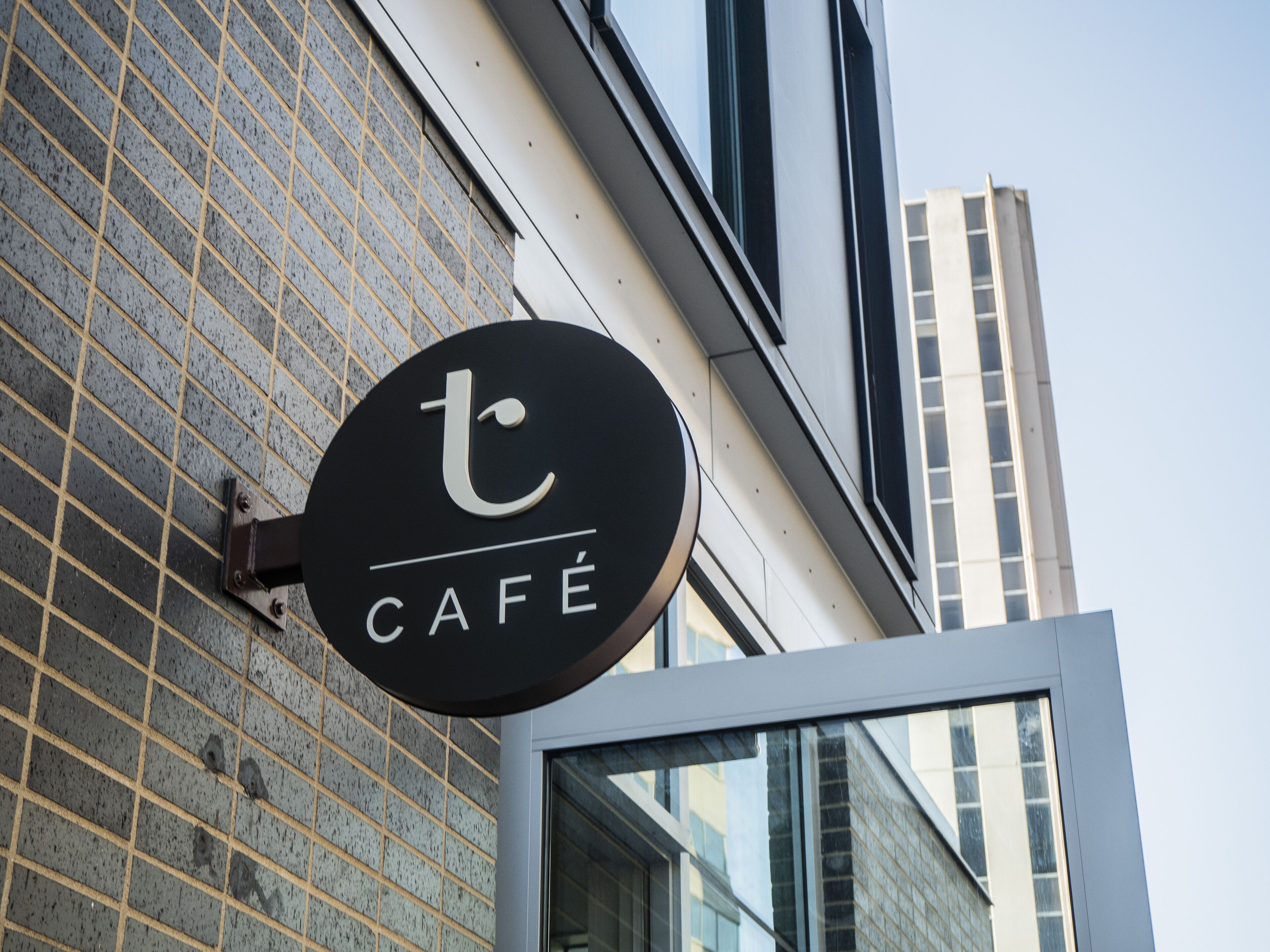 Letrero de café con un diseño moderno, sujeto a una pared de ladrillo.