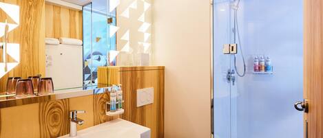 A modern bathroom with a wooden vanity, a glass shower enclosure, and a white sink.