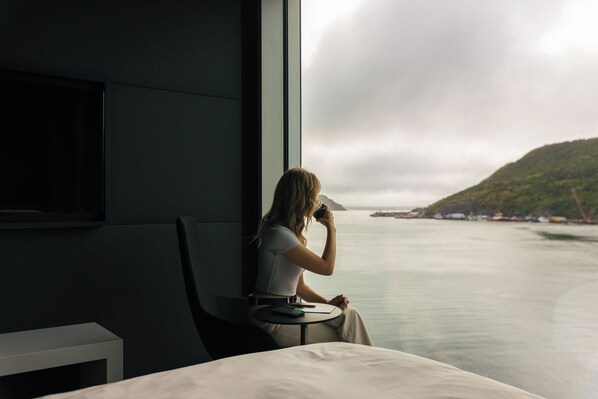 Una mujer sentada junto a una ventana con vistas a un cuerpo de agua y una isla distante.