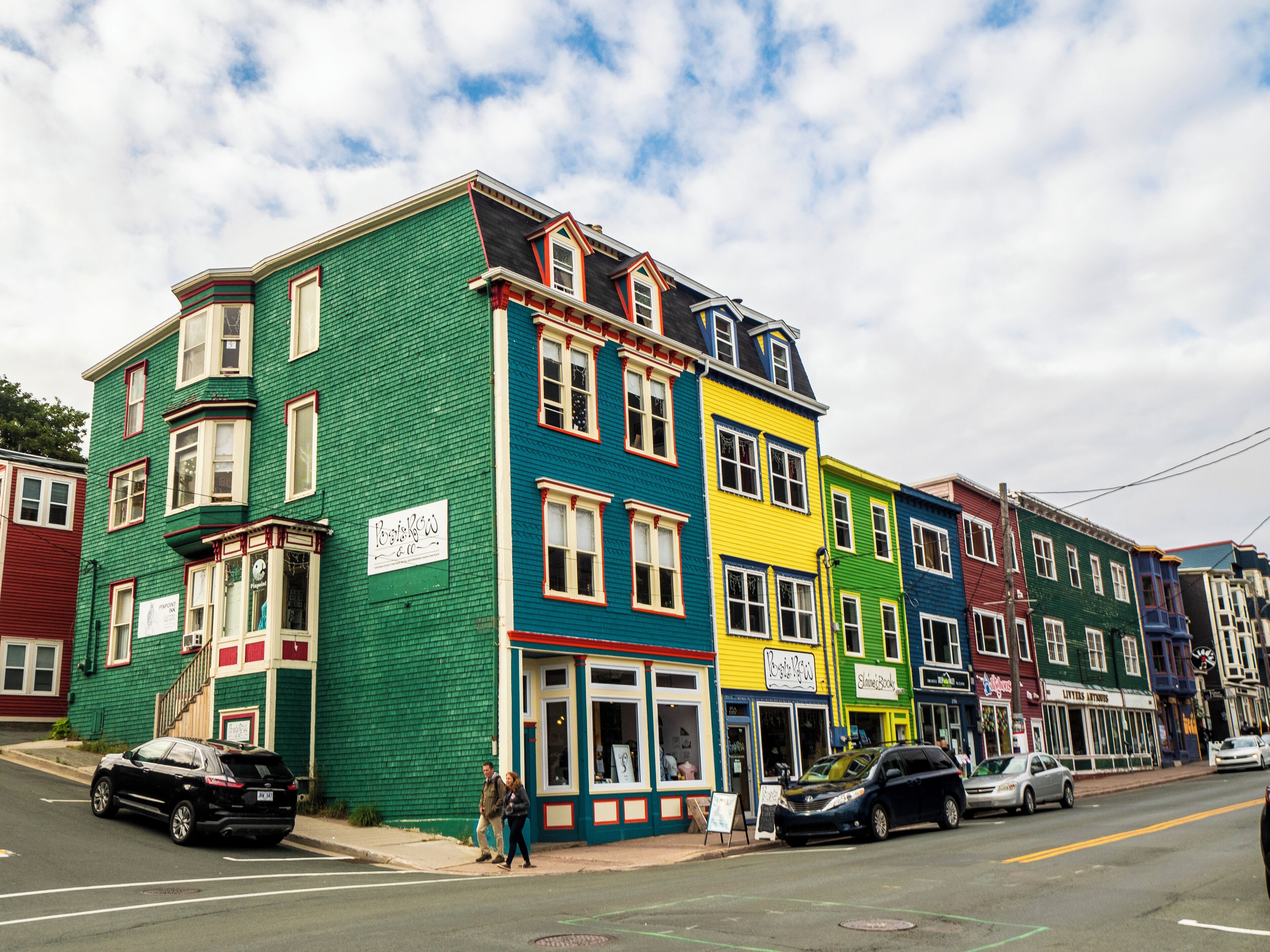 A row of colorful, multi-story buildings with various storefronts on the ground floor.