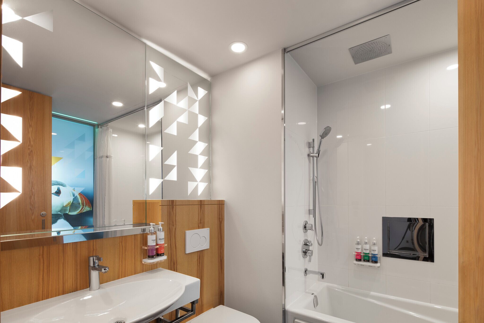 Un baño moderno con cabina de ducha de vidrio, tocador de madera y un espejo grande.