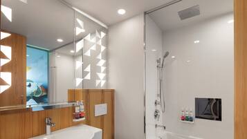 Un baño moderno con cabina de ducha de vidrio, tocador de madera y un espejo grande.