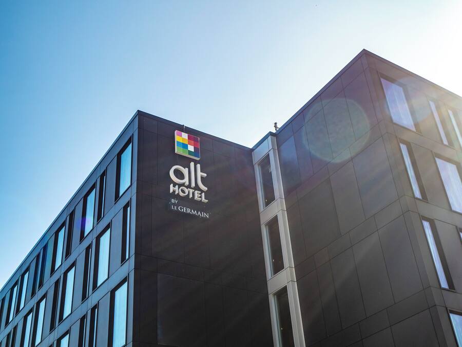 A modern hotel building with a prominent logo and name on the facade.