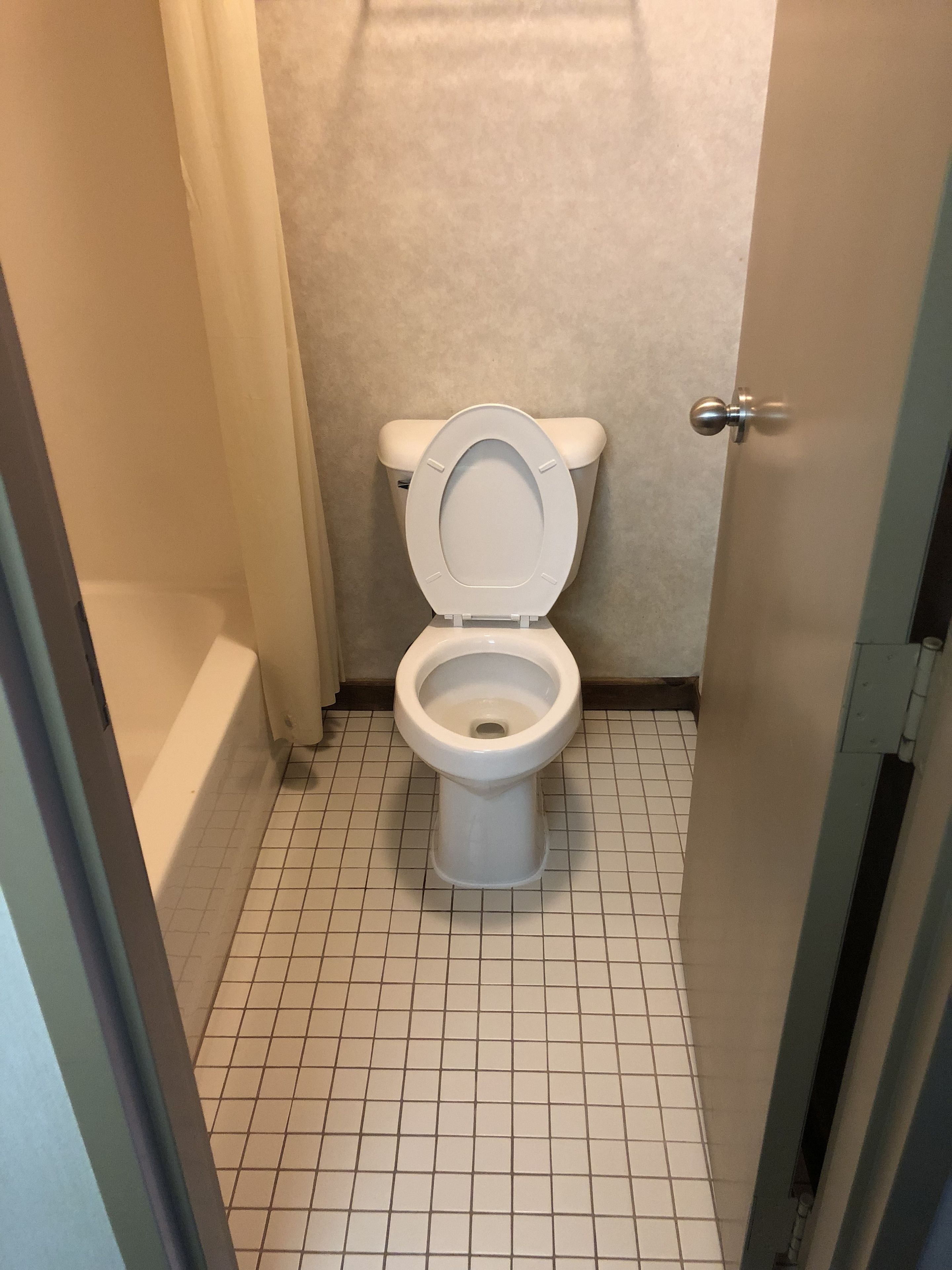 Un baño con inodoro, bañera y suelo de baldosas.