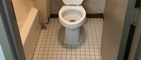 A bathroom with a toilet, a bathtub, and a tiled floor.