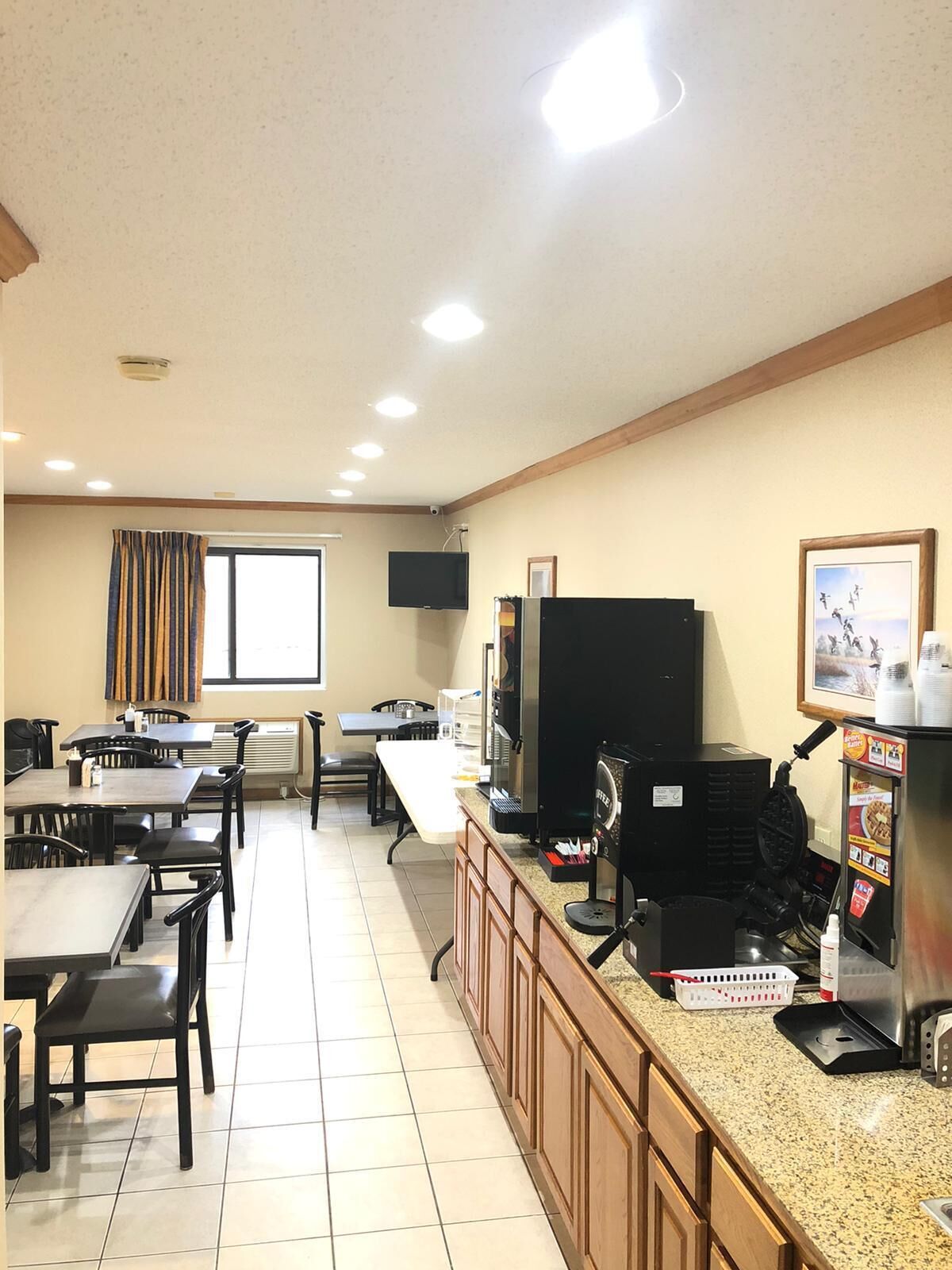 A restaurant with tables and chairs, a television, and a coffee machine.