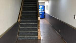 Un pasillo con una escalera, una máquina expendedora y un detector de incendios en la pared.