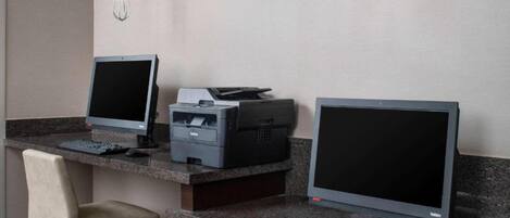 A workspace with two desktop computers, a printer, and two chairs.