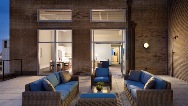 An outdoor patio area with wicker furniture and a glass door leading to an interior space.