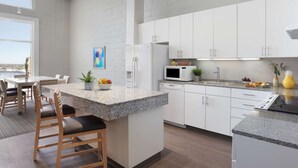 A modern kitchen with white cabinets, granite countertops, and a central island with bar stools.