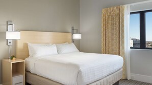 A hotel room with a large bed, two bedside lamps, a nightstand with a drawer, a window with curtains, and a city view.