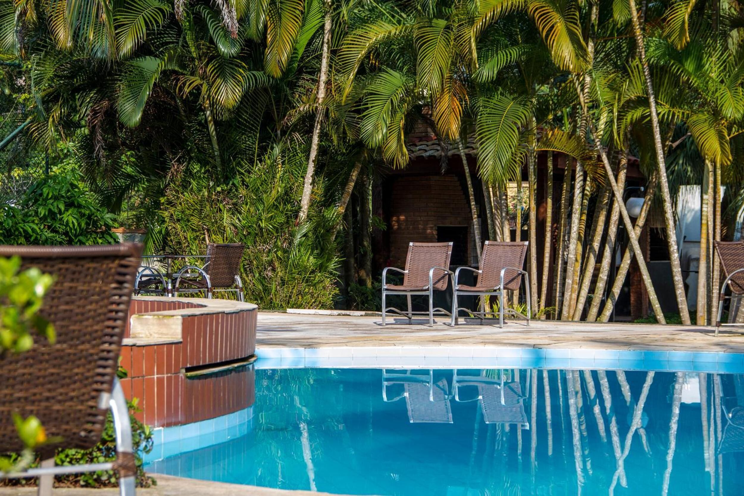 A swimming pool surrounded by lush greenery and wicker chairs.