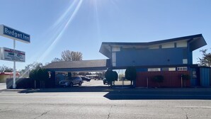 A Budget Inn with a sign indicating free HBO and WiFi, a covered parking area, and a building with a modern design.