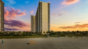 A beachfront hotel with high-rise buildings, a sandy beach, and a sunset sky. - Brighton Tower 1909 3br 3ba Oceanfront 3 Bedroom Condo by RedAwning (Myrtle Beach)