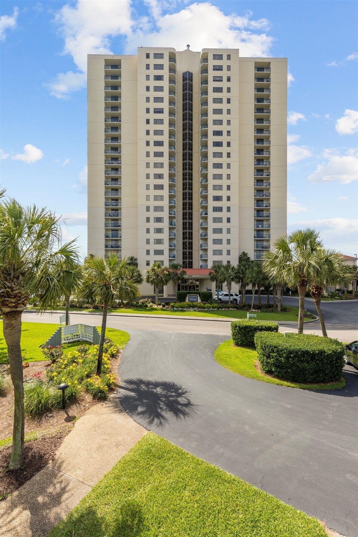 A multi-story hotel with a central courtyard, surrounded by palm trees and well-maintained lawns.