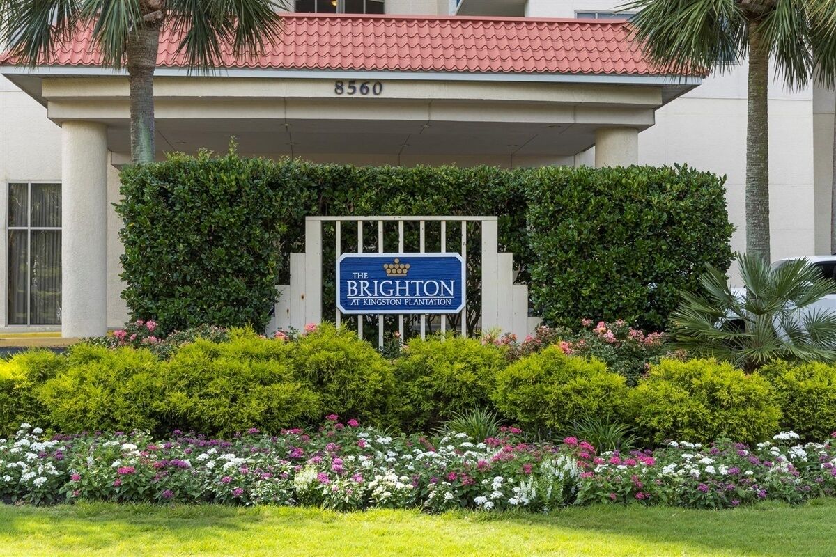 A sign for 'The Brighton at Kingston Plantation' with a well-maintained garden in front.