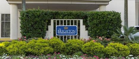 Un letrero que dice 'The Brighton at Kingston Plantation' con un jardín bien cuidado al frente.